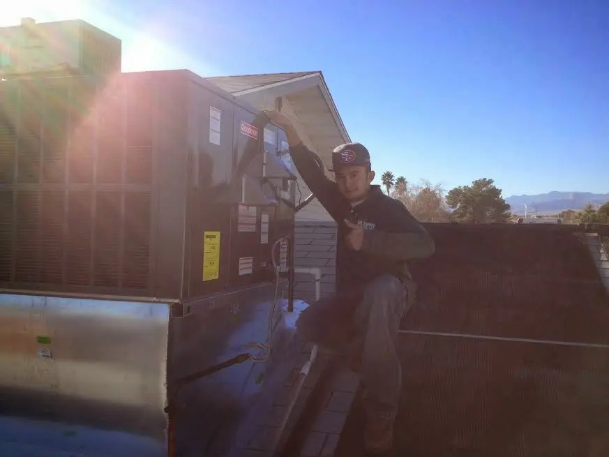 HVAC technician performing Air Duct Cleaning on a rooftop unit in Glenpool