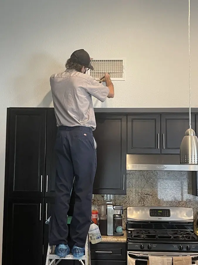 Technician inspecting an air vent during HVAC service in Glenpool